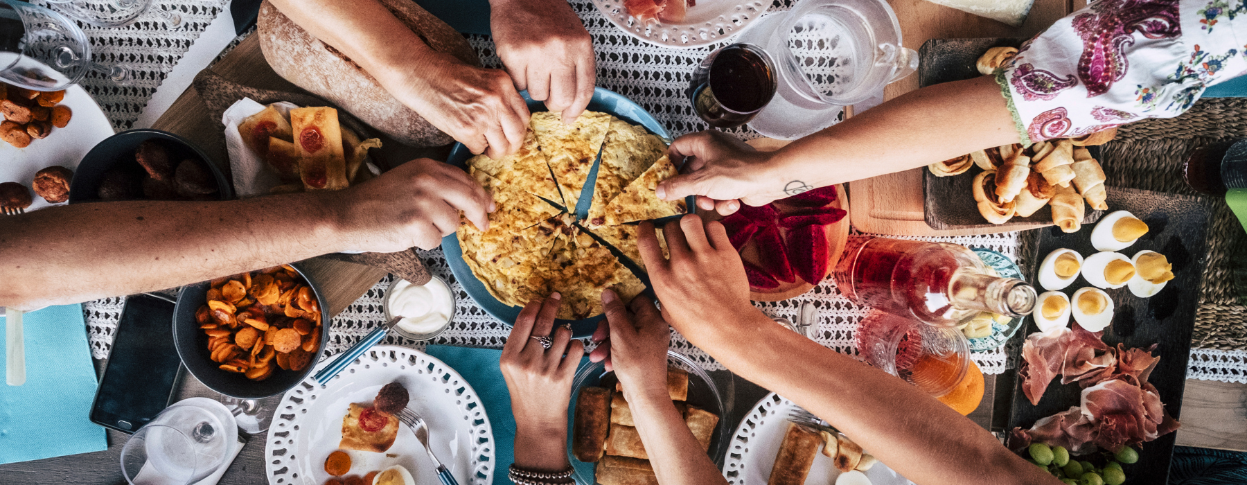 people with hands in together at a dinner table eating